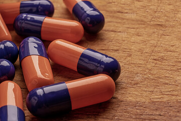 Blue and orange pills on wooden table, organic treatment from mother-nature - 561213013