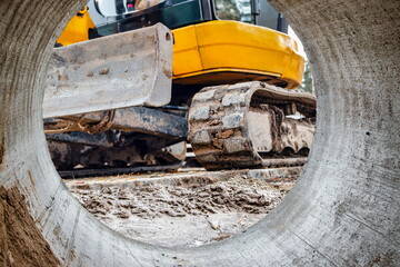 Close-up mini excavator during the construction of a modern residential complex. Miniature construction equipment for working in cramped conditions. - obrazy, fototapety, plakaty