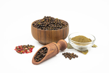 Black pepper, ground black pepper in a glass bowl, mixed pepper, bay leaf isolated on a white background.