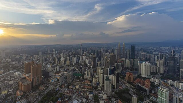 Aerial day-time time lapse overlooking a wide view of a city skyline with dancing rays before sunset in Kuala Lumpur, Malaysia. Zoom in motion timelapse.
