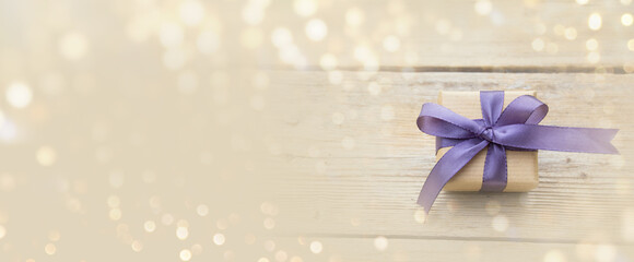 Gift box with purple bow and bokeh lights. Happy Birthday, Mother's Day or Wedding card with copy...