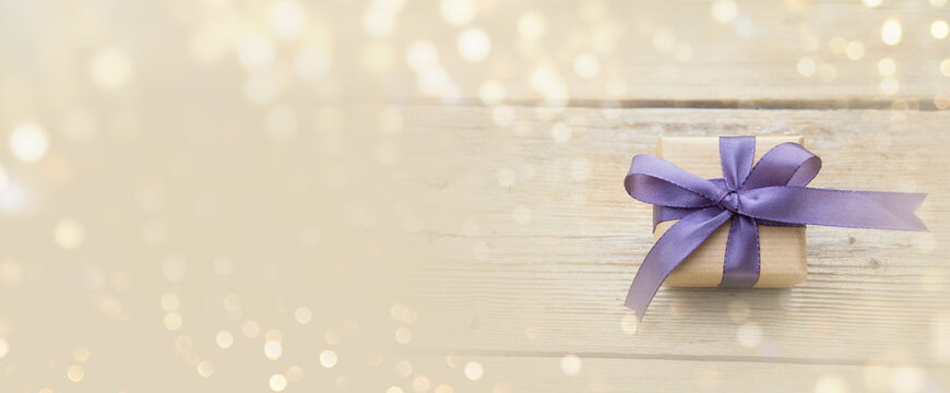 Gift box with purple bow and bokeh lights. Happy Birthday, Mother's Day or Wedding card with copy space