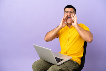 Young man sitting on a chair with laptop shouting and announcing something