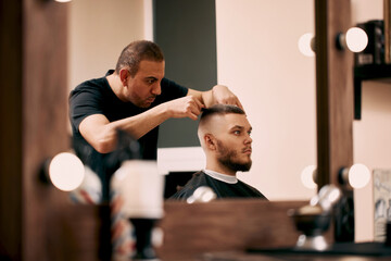 hairdresser does hairstyle with scissors in barber shop
