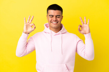 Young handsome man over isolated yellow background in zen pose