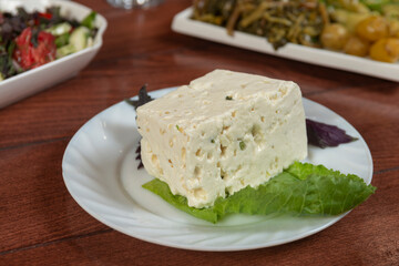 Big white piece of asian Korean tofu soy cheese on wooden board with greens