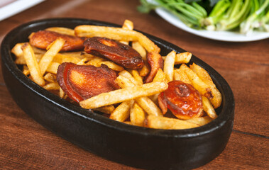 Frying pan with pieces fried sausage and potato