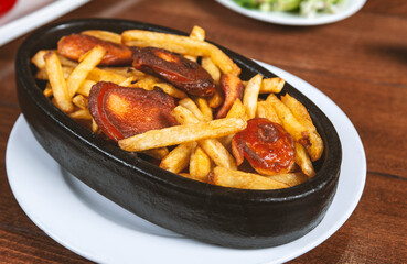 Frying pan with pieces fried sausage and potato