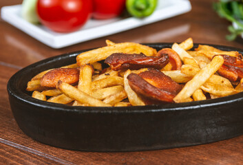 Frying pan with pieces fried sausage and potato