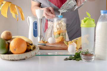 Pour the protein into a measuring spoon. Measure out ingredients with a measuring spoon. Preparing a sports cocktail.