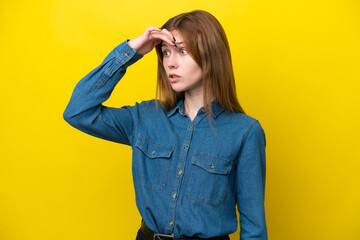 Young English woman isolated on yellow background doing surprise gesture while looking to the side