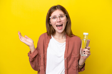 Young English woman with a bottle of water isolated on yellow background with shocked facial expression