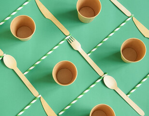 Eco-friendly disposable utensils made of bamboo wood and paper on green background. Environmental...