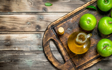 Apple cider vinegar with green apples on an old Board.