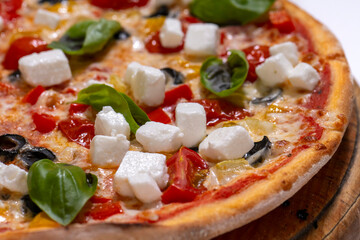 freshly baked pizza with feta cheese slicers on white background