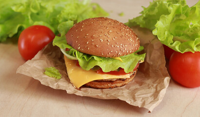Cheeseburger with chicken cutlet close-up. Burger with cutlet, melted cheese, salad and vegetables. Fast food