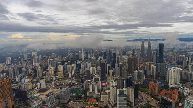 Aerial sunrise time lapse overlooking a wide view of a city skyline with dancing rays before sunset in Kuala Lumpur, Malaysia. Pan right motion timelapse. Prores 4K DCI