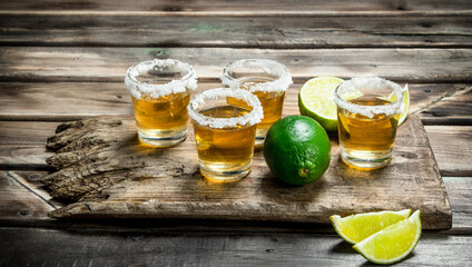 Tequila in a shot glass on a cutting Board with lime.