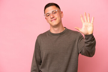 Young Brazilian man isolated on pink background counting five with fingers