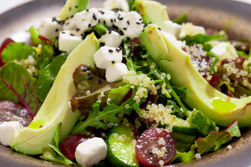 Bowl of vegetables salad with avocado on white background
