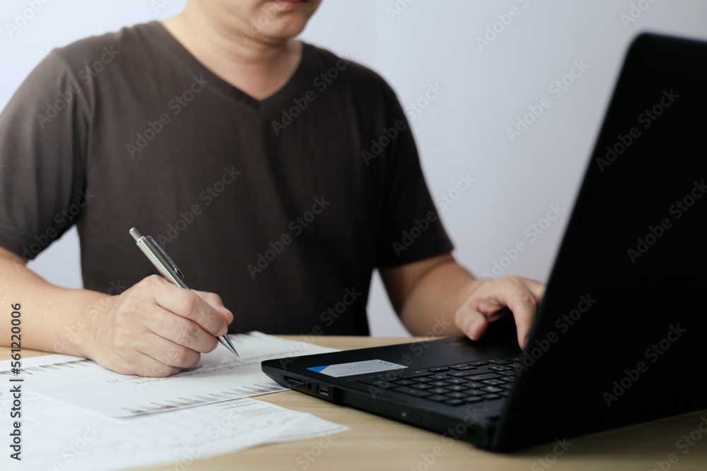Poster man using laptop computer and taking notes in planning. which is payment online, sits on the chair i
