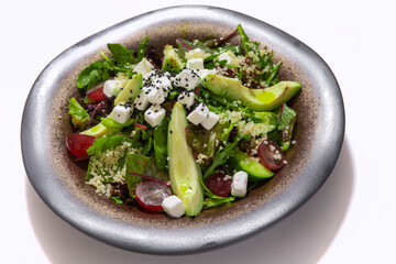 Bowl of vegetables salad with avocado on white background
