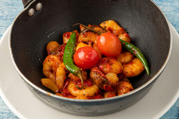 Shrimp casserole with tomatoes, garlic and peppers in black wok pan