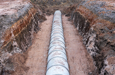Large circular concrete sewer mounted in the ground awaiting a landfill.