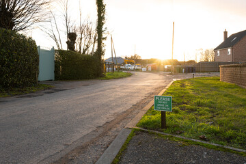 Naklejka premium Shallow focus of a small and polite No Parking sign seen on a grass verge outside a private house.