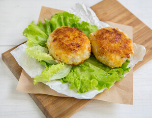 Delicious poultry cutlets. dietary product. Two cutlets lie on a wooden board with a lettuce leaf.