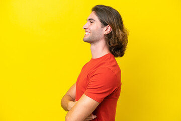 Caucasian handsome man isolated on yellow background in lateral position