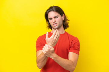 Caucasian handsome man isolated on yellow background suffering from pain in hands