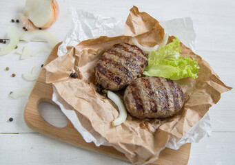 Delicious cutlets from deit meat. Two cutlets lie on a wooden board with a lettuce leaf.