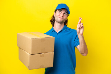 Fototapeta na wymiar Delivery handsome man isolated on yellow background with fingers crossing and wishing the best