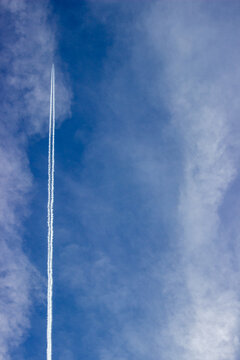 Plane in the sky with cloud trail and clouds semi clear sky