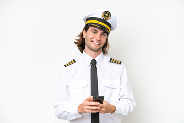 handsome Airplane pilot isolated on white background sending a message with the mobile