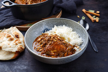 Traditional spicy Indian chicken Madras curry Rogan Josh with chicken, chapati bread and basmati rice served as close-up in a Nordic design bowl