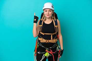 Young caucasian rock climber woman isolated on blue background pointing with the index finger a great idea