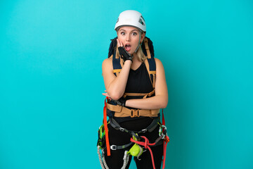 Young caucasian rock climber woman isolated on blue background surprised and shocked while looking right