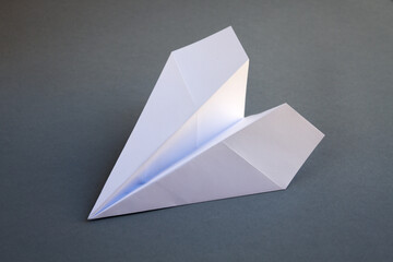 White paper plane origami isolated on a grey background