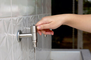 Asian woman opening faucet to wash hands Clean before and after touching food. Soft and selective focus.