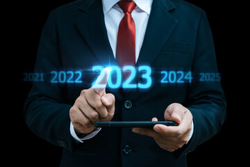 Fototapeta na wymiar 2023. businessman hand touching and pointing on year 2023 with virtual screen on dark background, goal target, change from 2022 to 2023, strategy, investment, business planning, happy new year concept