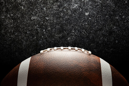 American football ball on dark textured background with space for text.