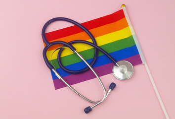 Stethoscope on rainbow LGBT flag on pink background. 