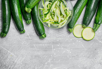 Pieces of zucchini in a bowl and a fresh whole zucchini.