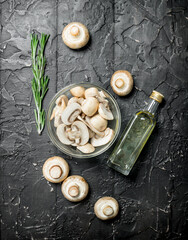 Mushrooms in a glass bowl and oil in a bottle.