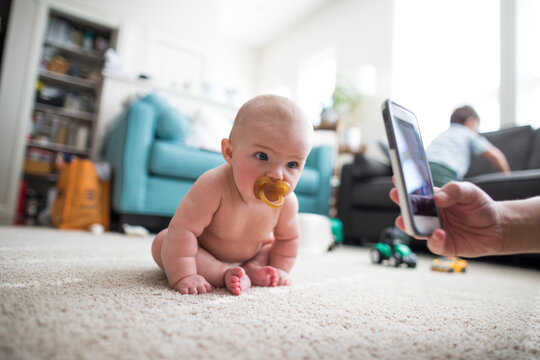 Parent photographing sitting baby