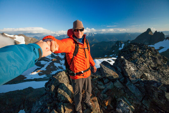Two climbers fist bump after successfully reaching the summit of Stewart Peak.
