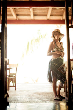 A woman in straw hat and beach attire at the entrance to a beach side cantina in Mexico.