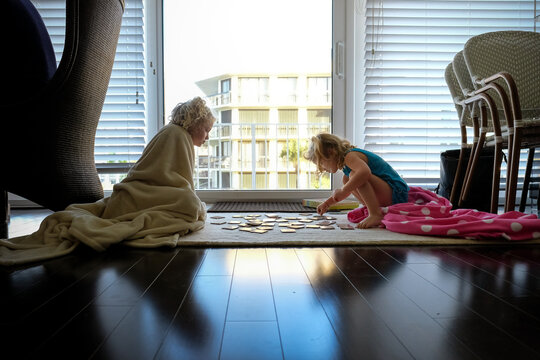 little girls play card game sitting on rug cuddling in blankets